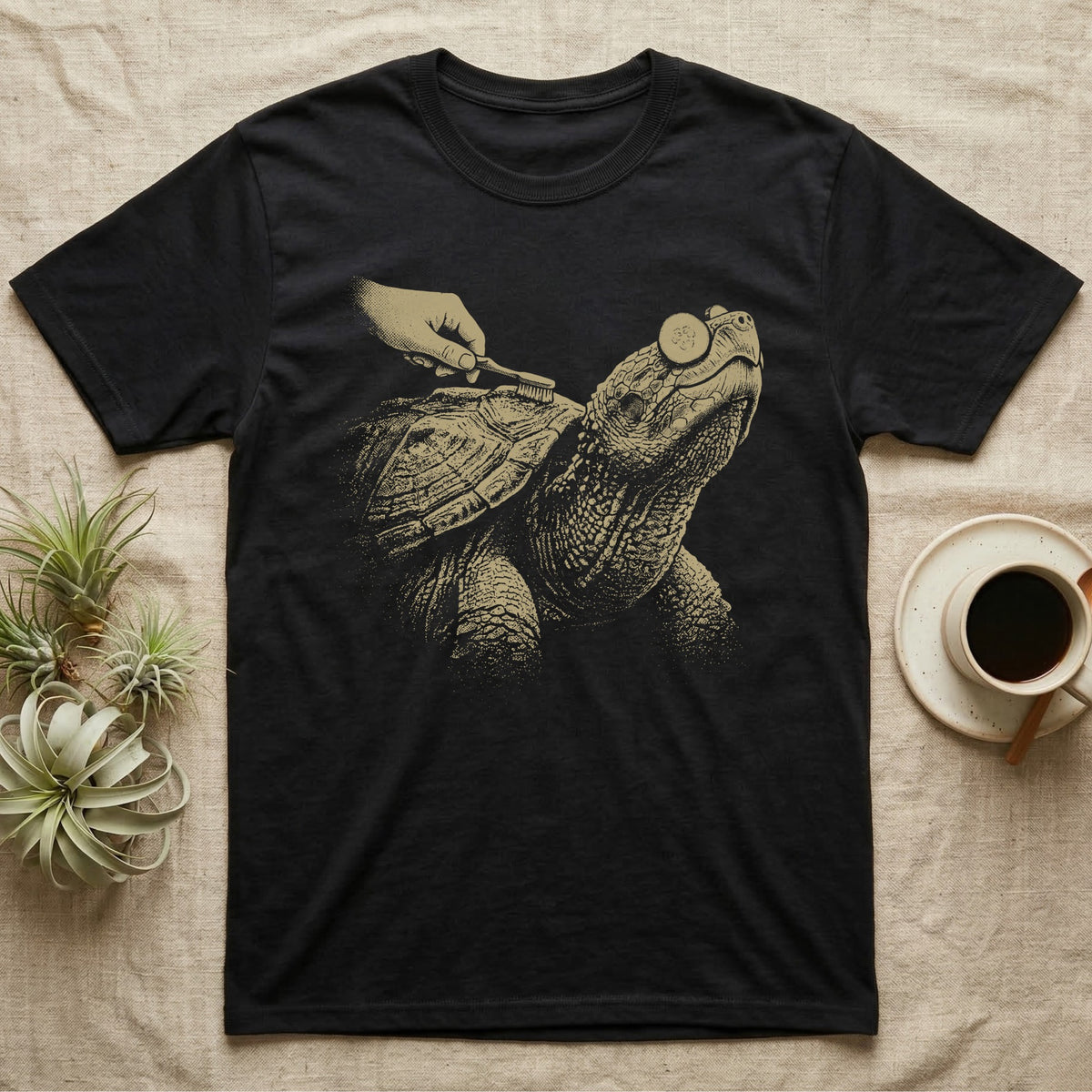 Snapping Turtle Spa T-Shirt in Black — Single-ink snapping turtle with cucumber slices on its eyes, chin up, while a hand scrubs its shell with a toothbrush.