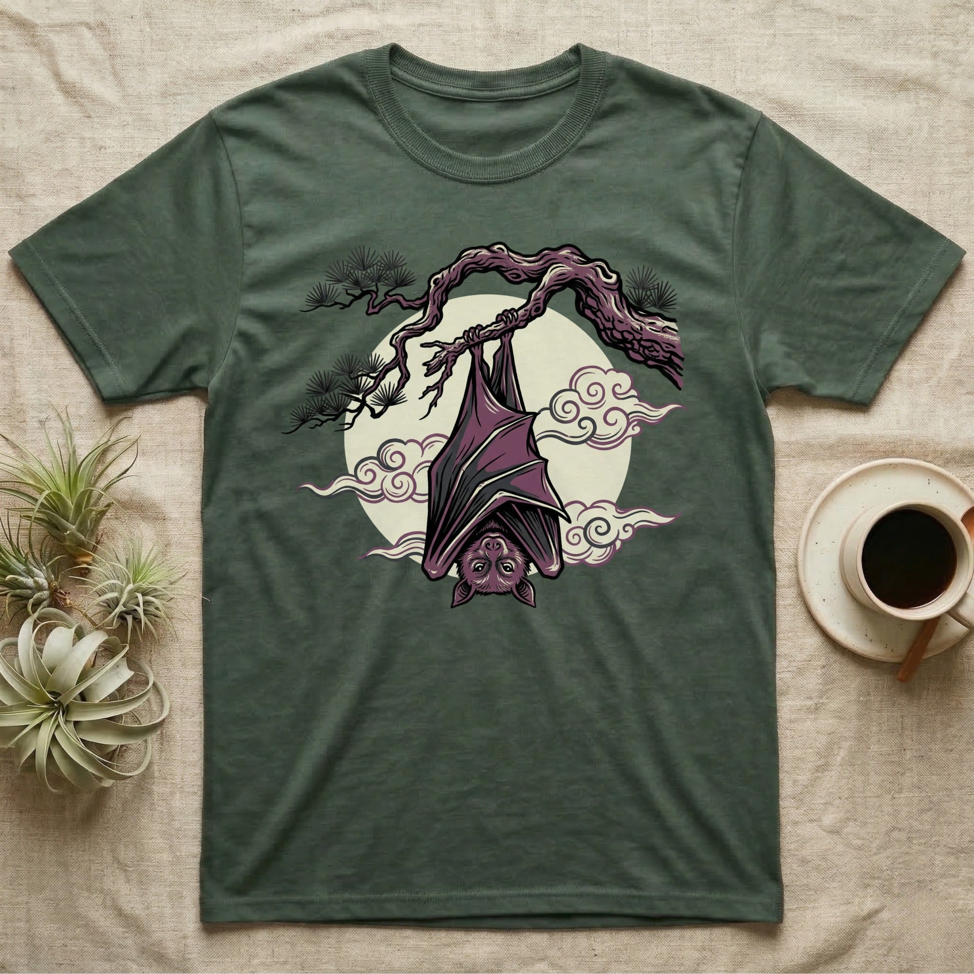 Green t-shirt with a bat hanging from a branch against a moon and clouds.
