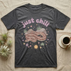 Rosy Boa Softie T-Shirt in Dark Heather — Relaxed coiled rosy boa with sleepy eyes under pastel bubble text "just chill" with tiny hearts.