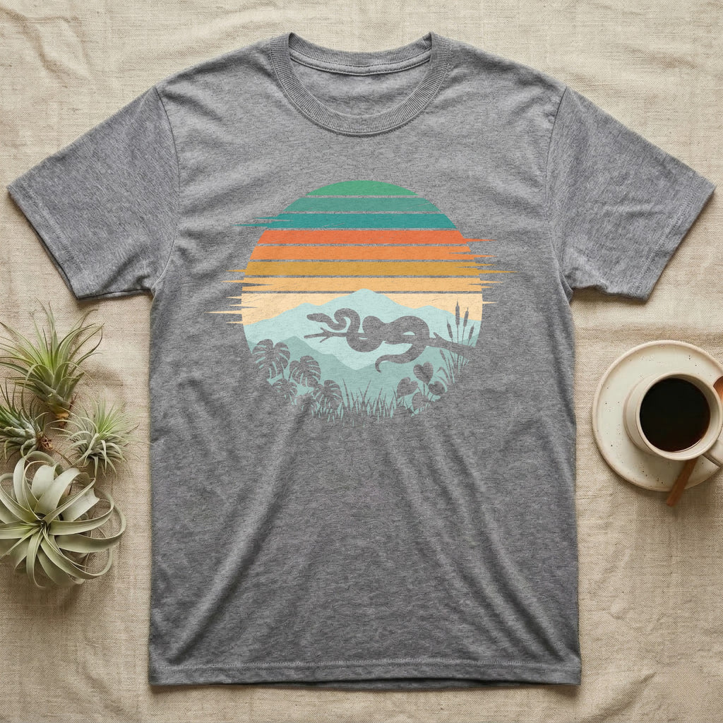 Ball Python Retro Sunset T-Shirt in Sport Grey — Ball python silhouette draped over a branch inside a retro striped sunset disc with monstera leaves on a tee
