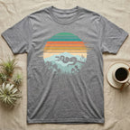 Ball Python Retro Sunset T-Shirt in Sport Grey — Ball python silhouette draped over a branch inside a retro striped sunset disc with monstera leaves on a tee