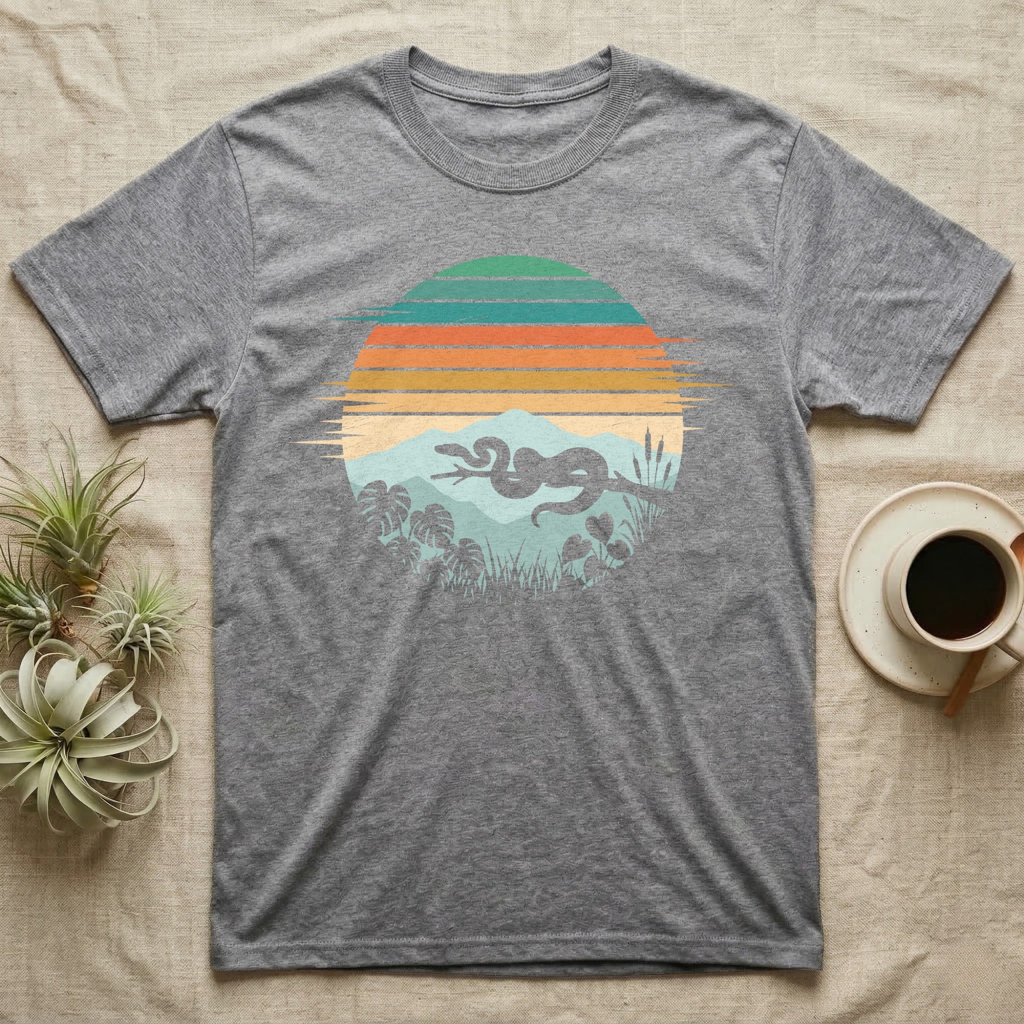 Ball Python Retro Sunset T-Shirt in Sport Grey — Ball python silhouette draped over a branch inside a retro striped sunset disc with monstera leaves on a tee