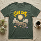 Moroccan Uromastyx Feral T-Shirt in Military Green — Moroccan uromastyx basking under a big sun with a jagged solar-gold metal "SUN GOD" wordmark and pastel desert scene.