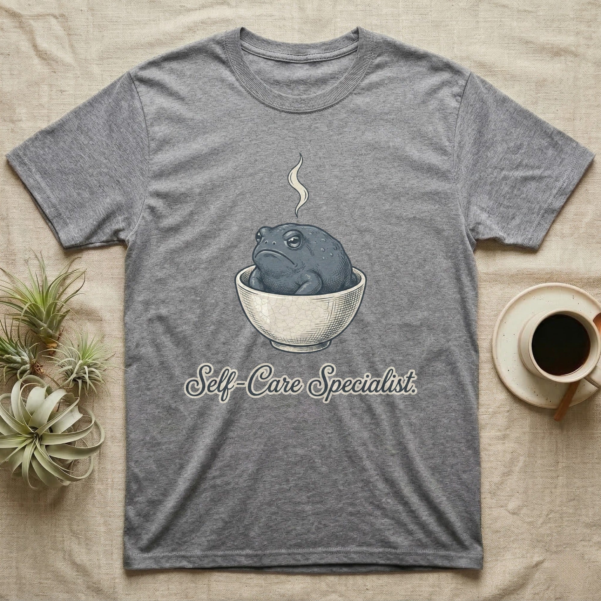 Gray t-shirt with a sad toad in a bowl, "Self-Care Specialist" text.