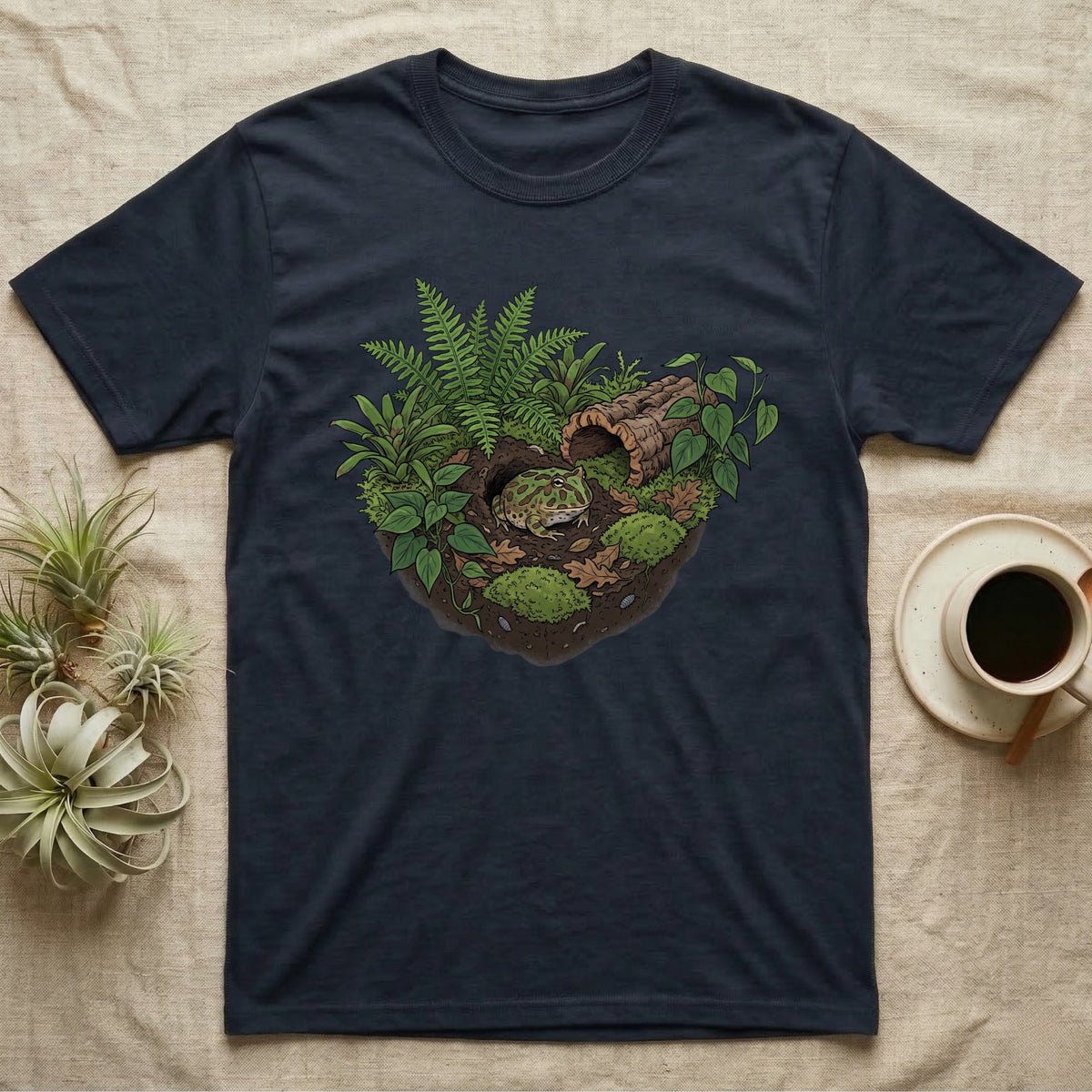 Pacman Frog Vivarium T-Shirt in Navy — Botanical illustration of a pacman frog thriving in a planted bioactive vivarium beside a small empty plastic cup.