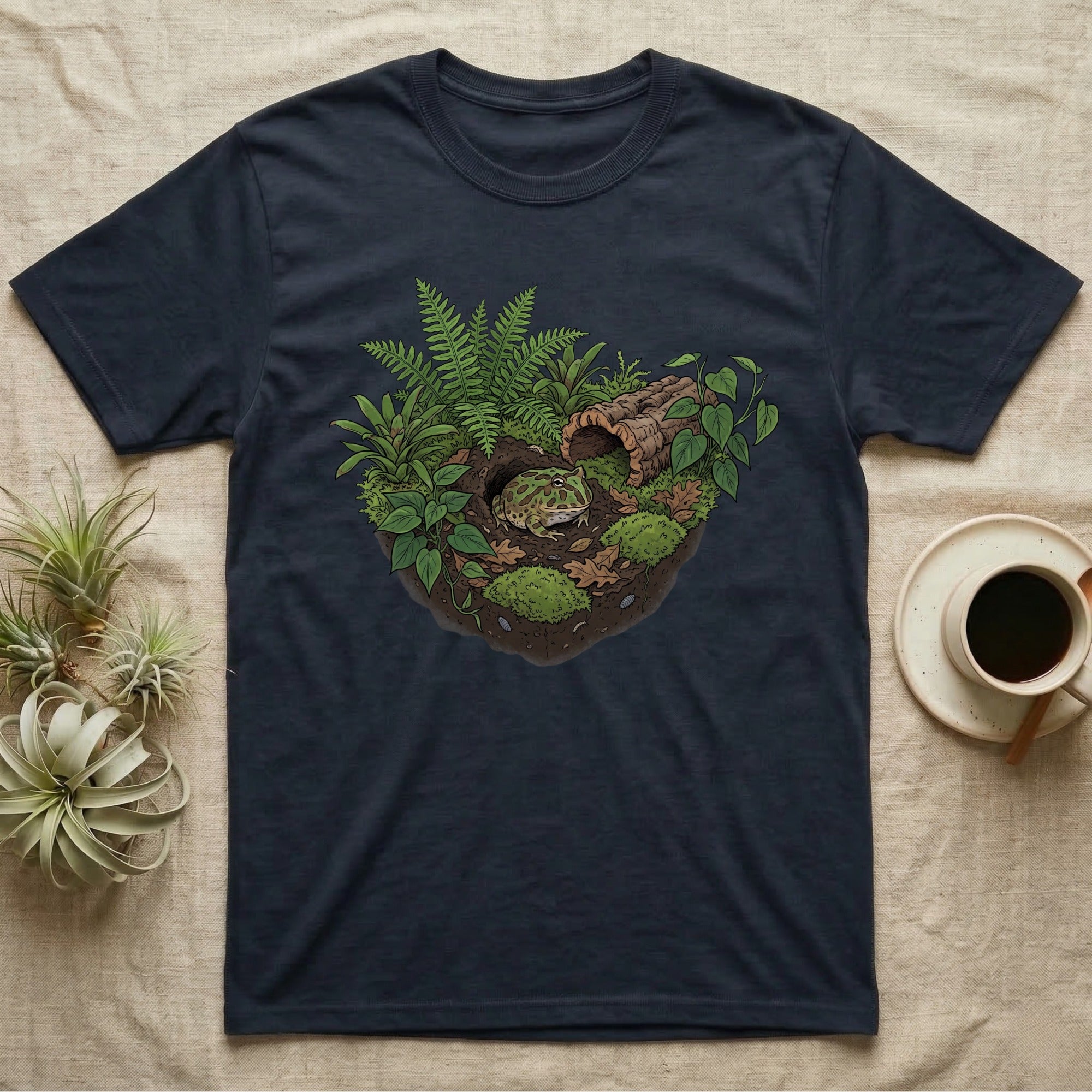 Pacman Frog Vivarium T-Shirt in Navy — Botanical illustration of a pacman frog thriving in a planted bioactive vivarium beside a small empty plastic cup.