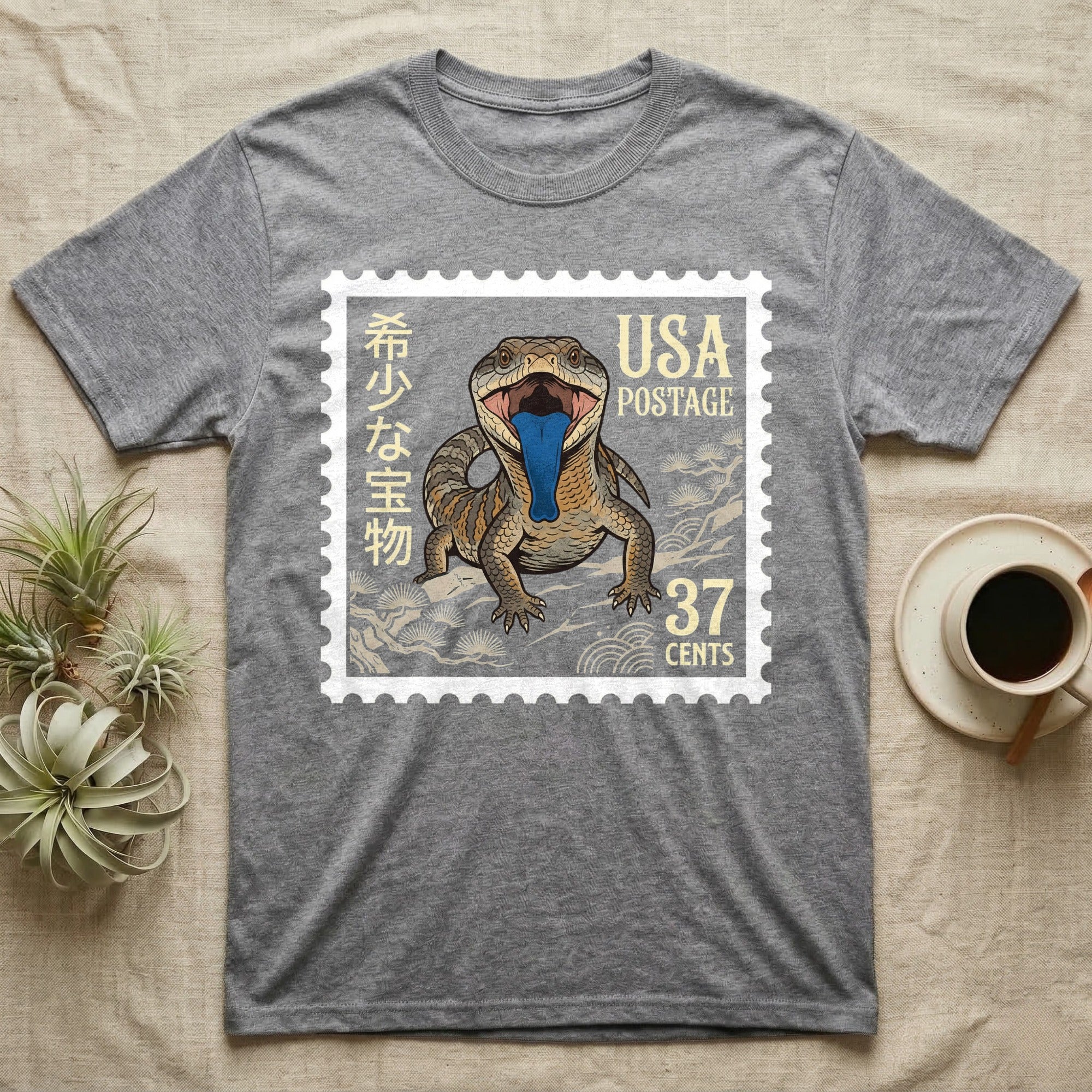 Grey t-shirt with a stamp featuring a lizard with blue tongue and "USA Postage 37 Cents".