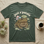 Cane Toad Baby T-Shirt in Military Green — Warty cane toad among pastel toadstools and lily pads under puffy cream bubble text "just a potato".