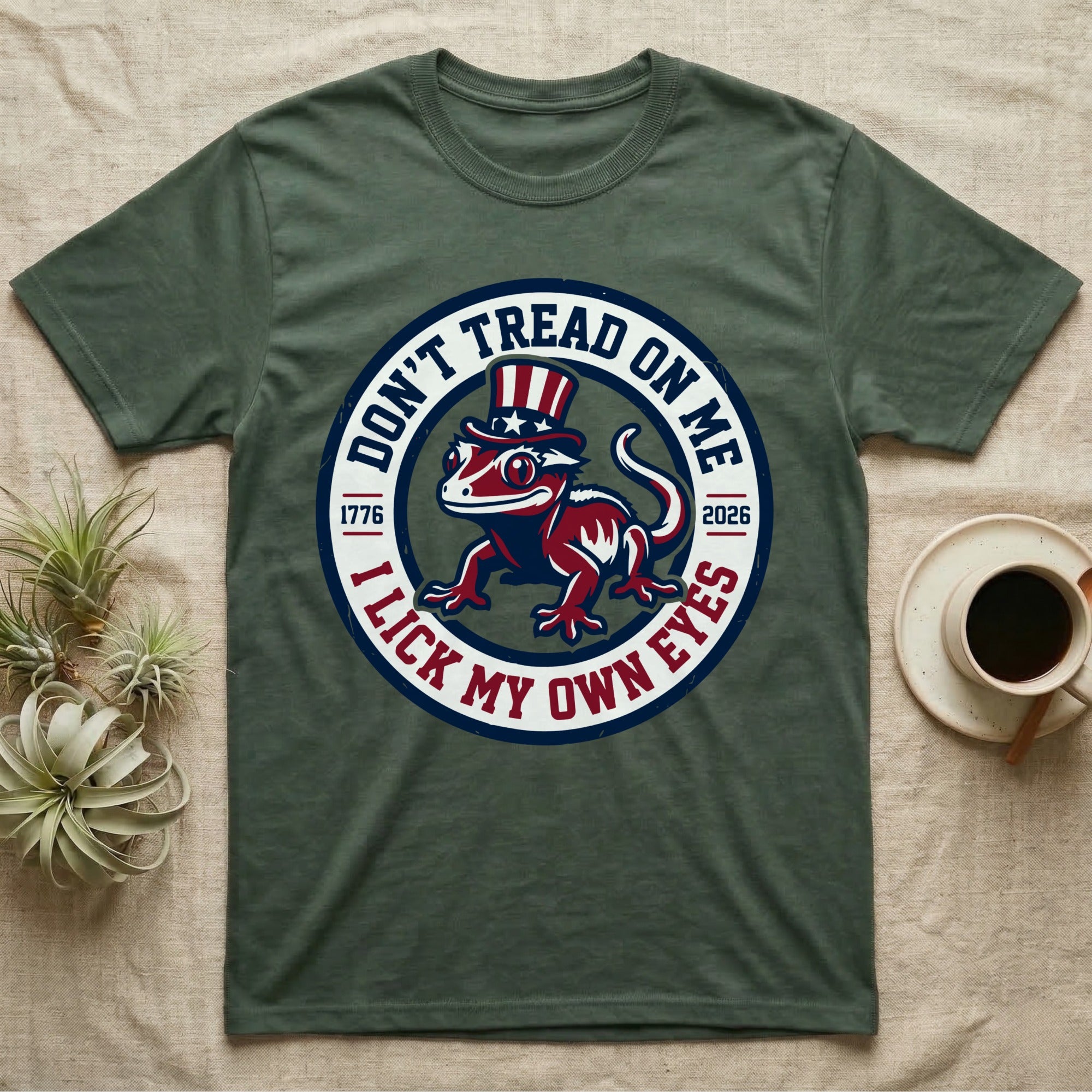 Crested Gecko 1776 T-Shirt in Military Green — Distressed crest of a crested gecko in a top hat with text Don't Tread On Me and I Lick My Own Eyes.