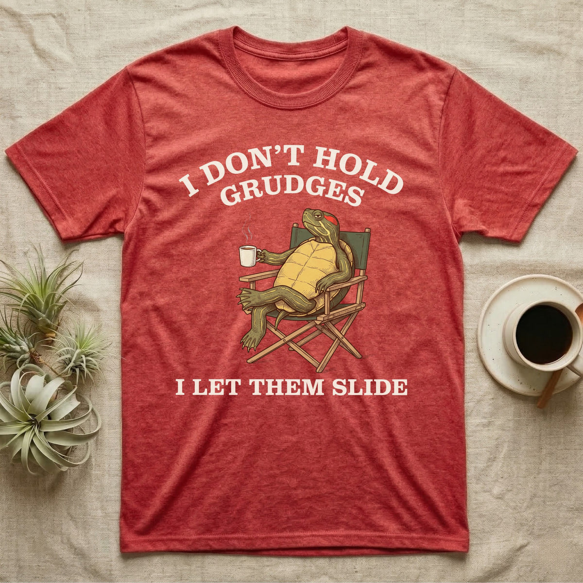 Red-Eared Slider Grudges T-Shirt in Heather Red — Engraved red-eared slider lounging in a camp chair with tea under I Don't Hold Grudges I Let Them Slide