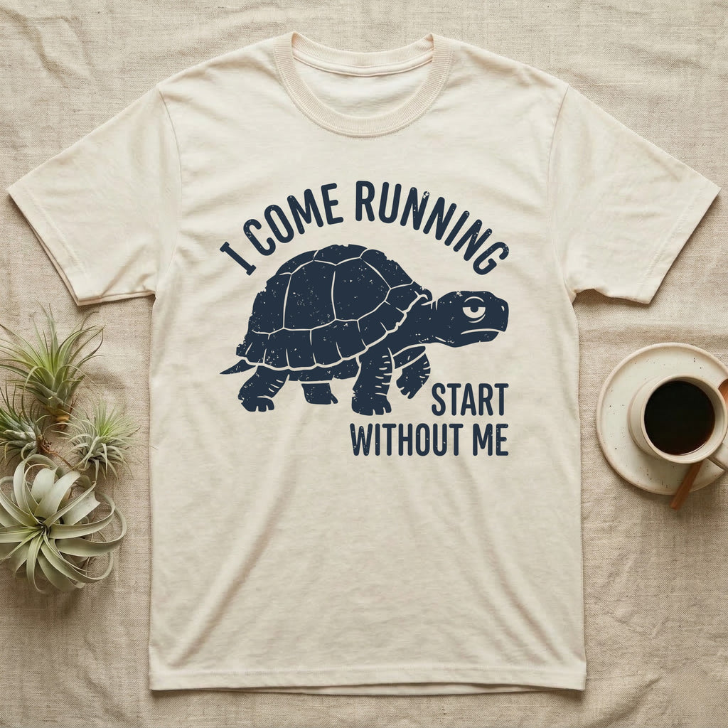Red-Foot Tortoise Running T-Shirt in Natural — Navy silhouette of a red-footed tortoise walking under arched words I Come Running, beside Start Without Me