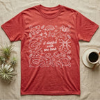 Terrarium Keeper One Tank T-Shirt in Heather Red — White outline illustration of eleven terrarium species — bearded dragon, crested gecko, ball python, axolotl, tortoise, tarantula, isopod, whip spider, chameleon, tree frog and hognose — with pothos and fern leaves, ringed around the script line it started with one tank.