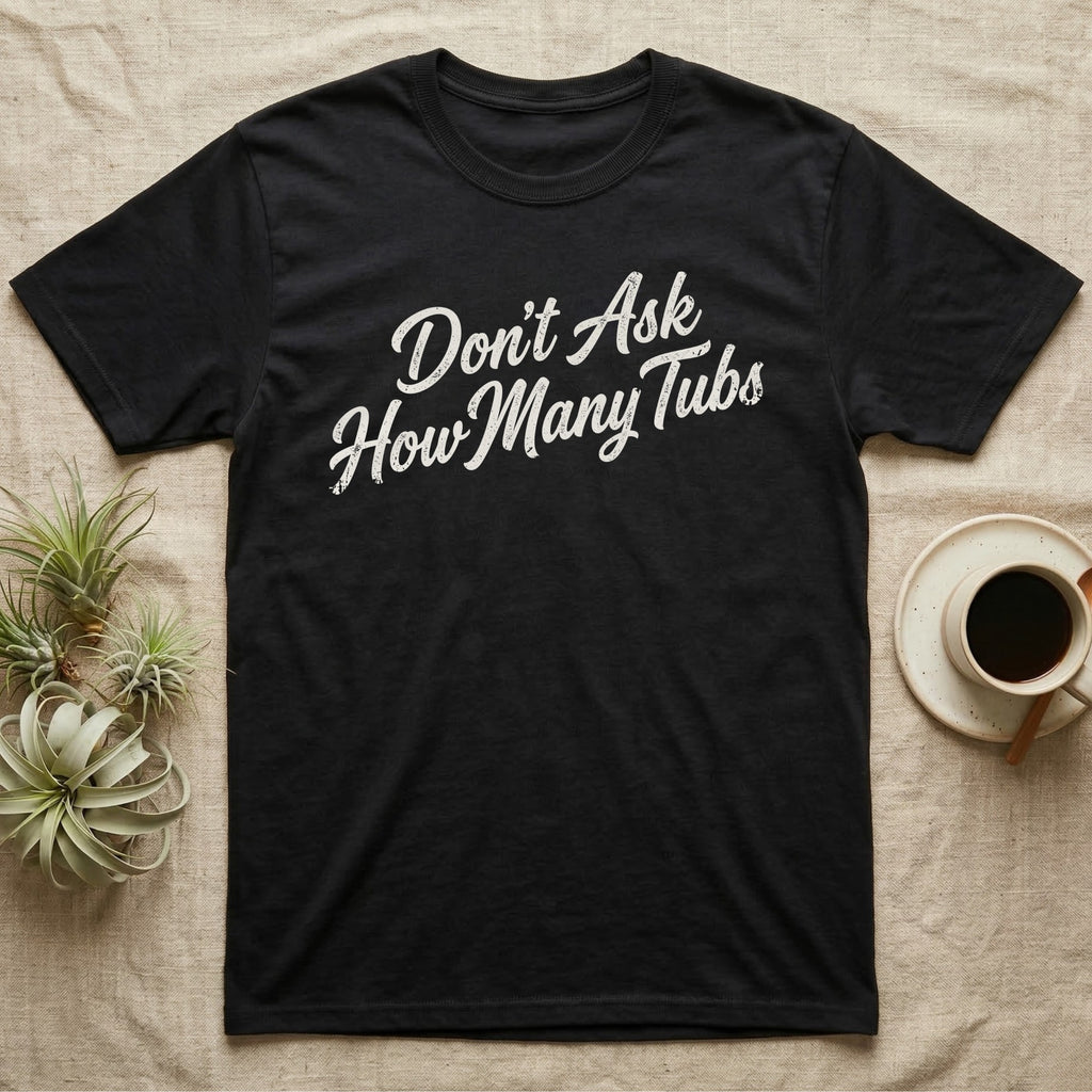 Snake Tubs T-Shirt in Black — Worn off-white 1970s retro brush script climbing a diagonal on charcoal, reading Don't Ask How Many Tubs
