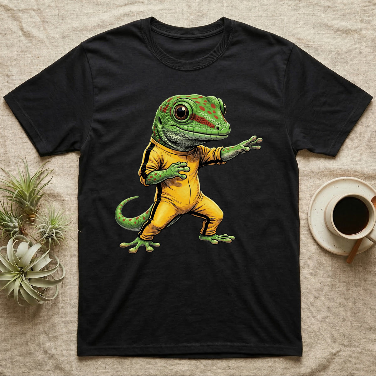 Anthropomorphic giant day gecko in a yellow-and-black martial-arts jumpsuit, low fighting stance, bold vintage-comic ink outlines and halftone shading, graphic-only design. — shown on a Black tee.