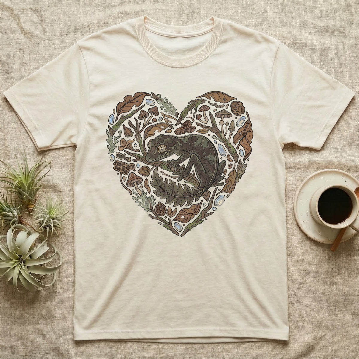 Cream t-shirt with a heart-shaped collage of natural elements and a gecko.