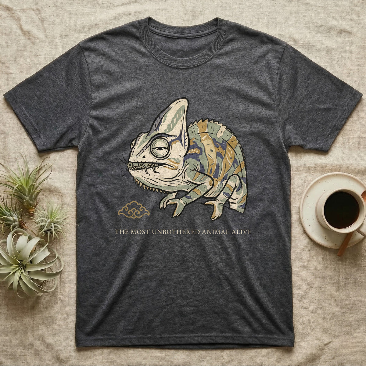 Unbothered Chameleon T-Shirt in Dark Heather — Ukiyo-e woodblock illustration of a veiled chameleon mid-chew with a deadpan serif caption beneath the subject.