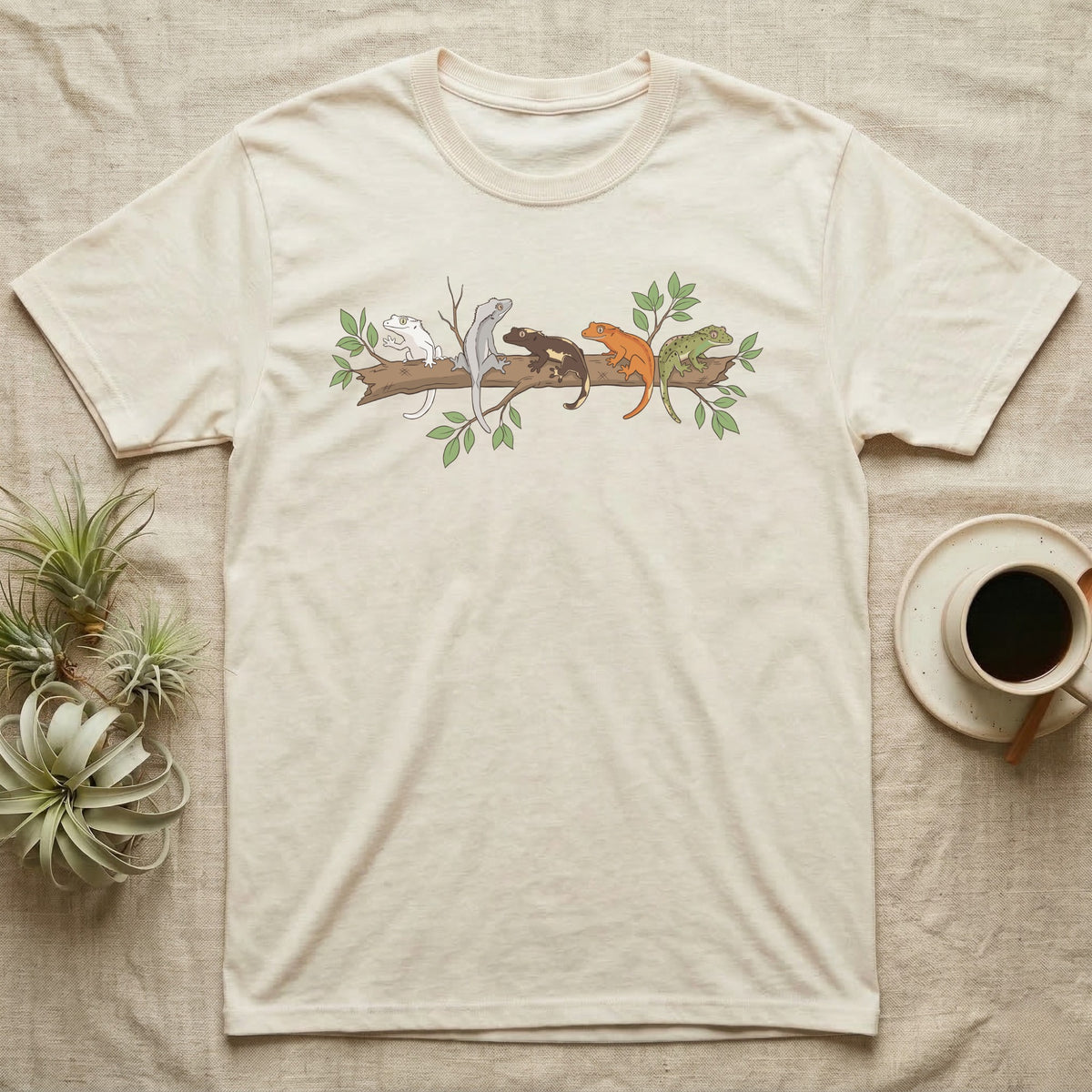 Crested Gecko Morph Line T-Shirt in Natural — Five crested gecko morphs in ink and watercolour perched along one cork bark branch with ficus leaves.