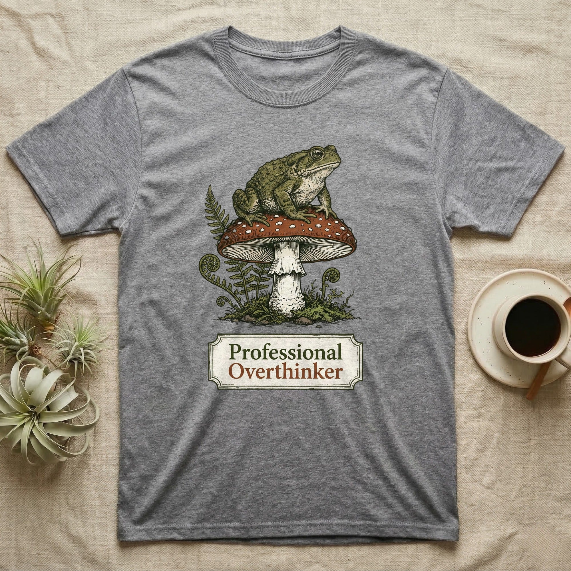 Grey t-shirt with a toad sitting on a mushroom, text reads "Professional Overthinker".