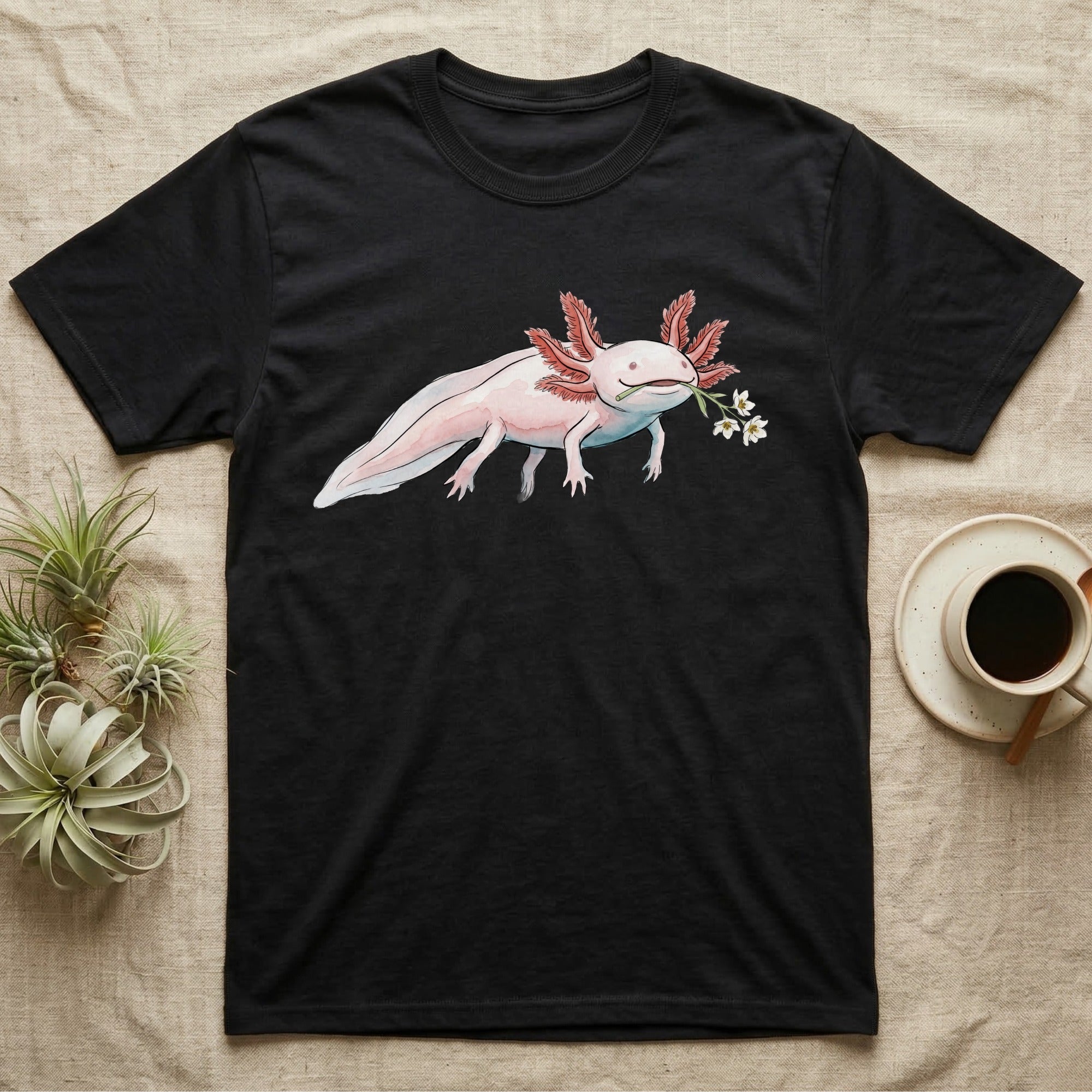Axolotl Blossom T-Shirt in Black — Watercolor illustration of a pink leucistic axolotl with feathery gills holding an aquatic blossom sprig, on a dark grey t-shirt.