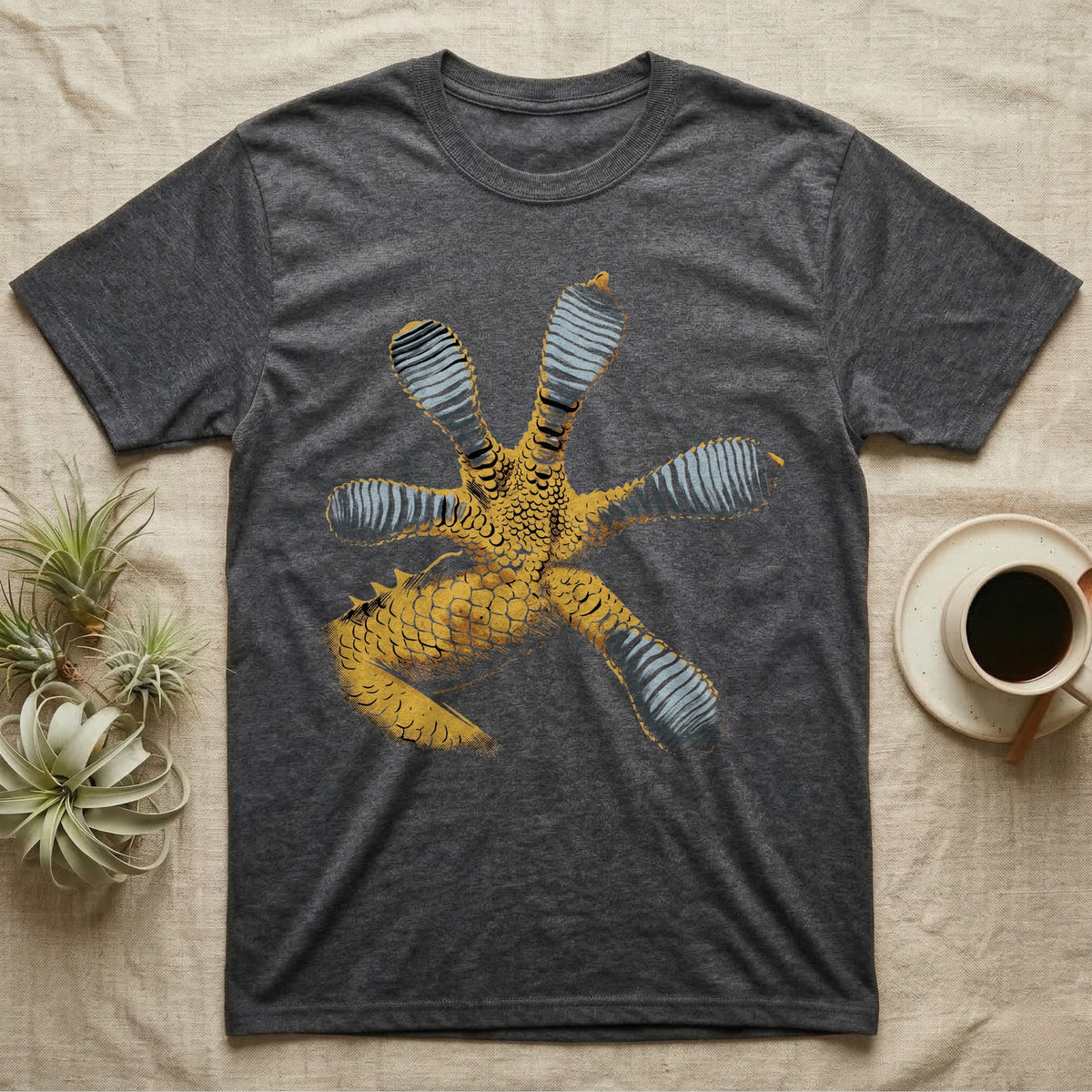Macro illustration of a gecko's forefoot from underneath, ribbed blue-grey lamellae toe pads fanned against amber-gold scale texture, no on-shirt text. — shown on a Dark Heather tee.