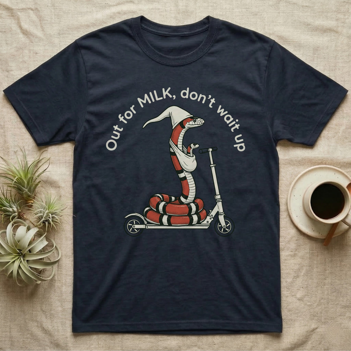 Milk Snake Scooter T-Shirt in Navy — Milk snake in a white cap riding a kick scooter with a baby snake in a sling, under the curved words Out for MILK, don't wait up.