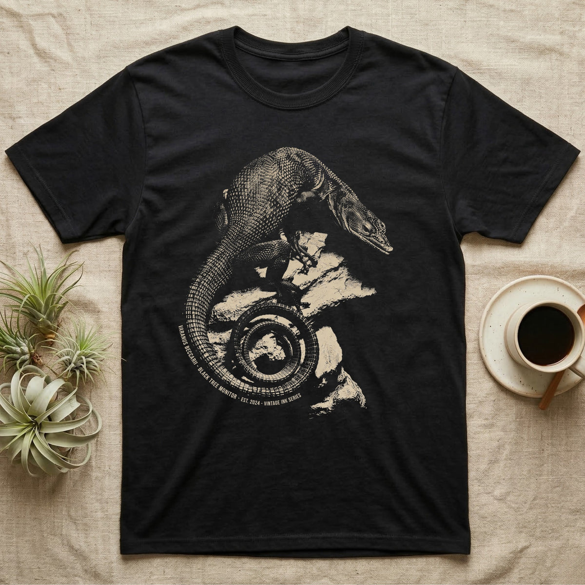 Vintage engraved illustration of a black tree monitor climbing rock with its tail coiled into a badge, arc text reading Varanus Beccarii, Black Tree Monitor, Est. 2024, Vintage Ink Series. — shown on a Black tee.