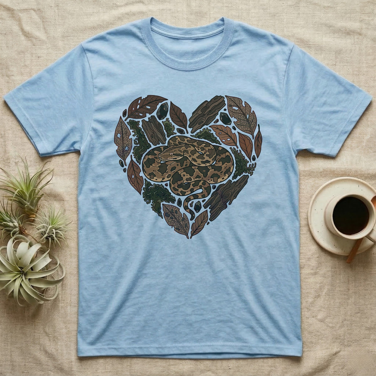 Light blue t-shirt with a heart-shaped design of a snake and natural elements.