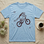 Tree Frog Can-Can T-Shirt in Light Blue — Distressed one-ink oxblood screenprint of a White's tree frog airborne on a BMX bike, both back legs kicked off the pedals and swung to one side, hands still on the bars.