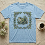 Light blue t-shirt with a central design of a frog surrounded by oak leaves and mushrooms.