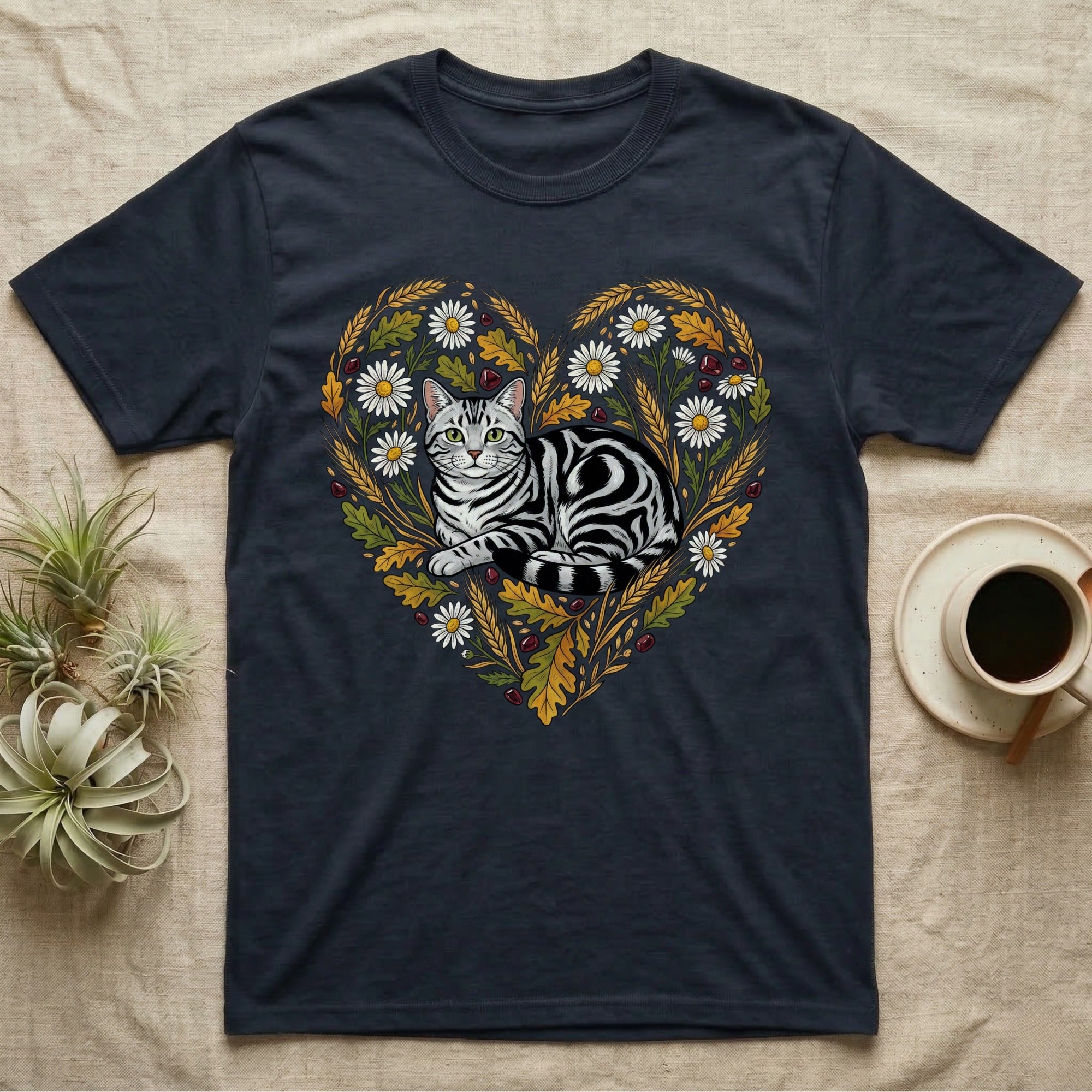 Dark t-shirt with a gray tabby cat in a heart-shaped floral and leaf design.