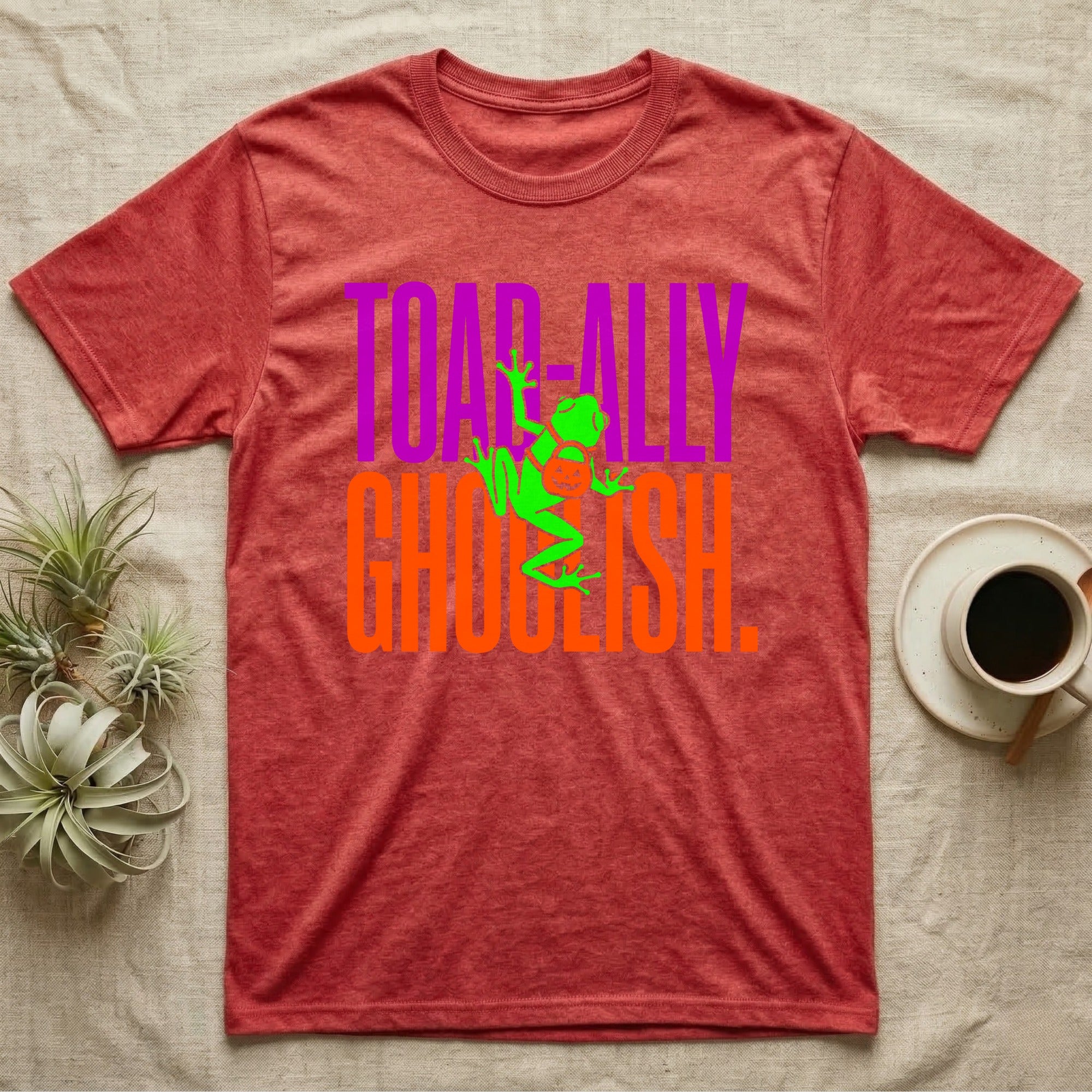 Tree Frog Toad-ally Ghoulish T-Shirt in Heather Red — Neon green tree frog with a pumpkin pail clinging across stacked text, "Toad-ally Ghoulish."
