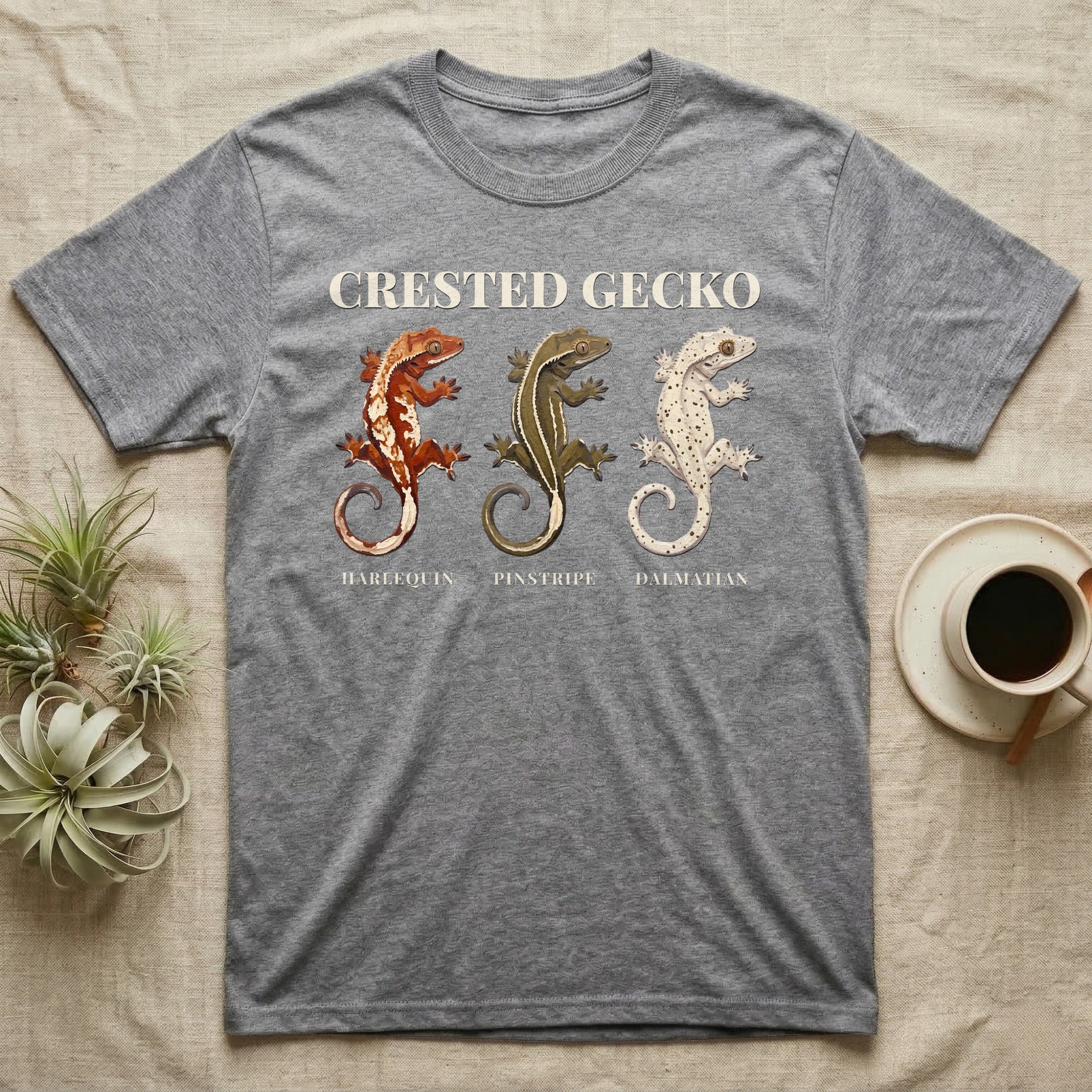 Crested Gecko Morph Chart T-Shirt in Sport Grey — Impasto painted chart of three crested gecko morphs — harlequin, pinstripe and dalmatian — labelled beneath each gecko.
