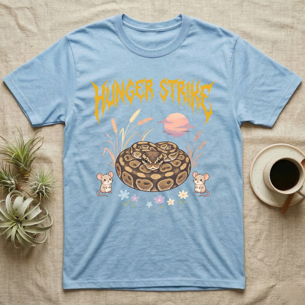 Ball Python Feral T-Shirt in Light Blue — Ball python coiled in a loaf in a pastel savanna scene under a spiky honey-gold metal wordmark reading HUNGER STRIKE.