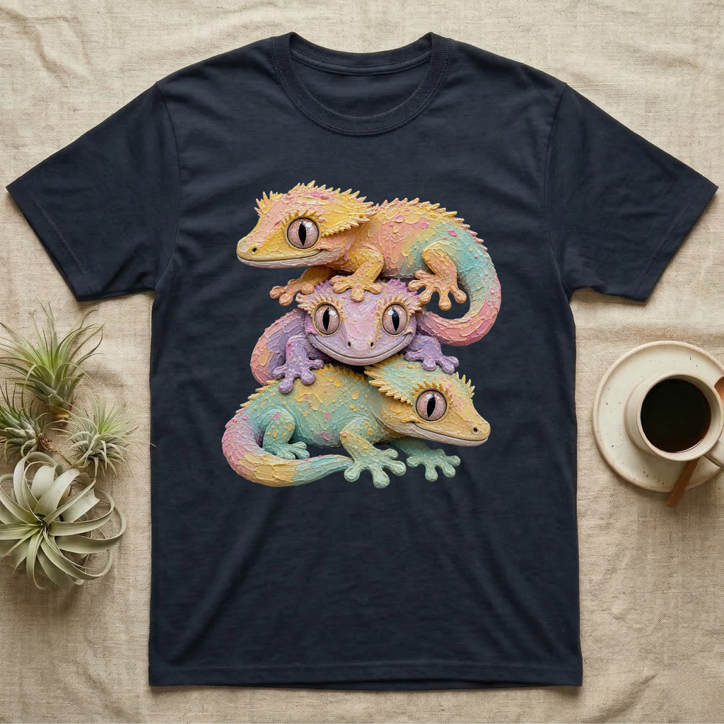 Three pastel-colored geckos stacked on a dark t-shirt.