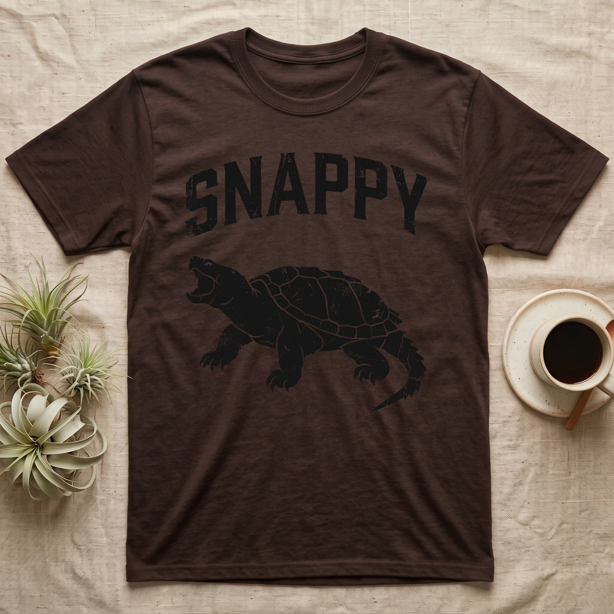 Snapping Turtle Snappy T-Shirt in Dark Chocolate — Worn one-ink print of a common snapping turtle crouched side-on, jaws open mid-snap, under the arched word SNAPPY