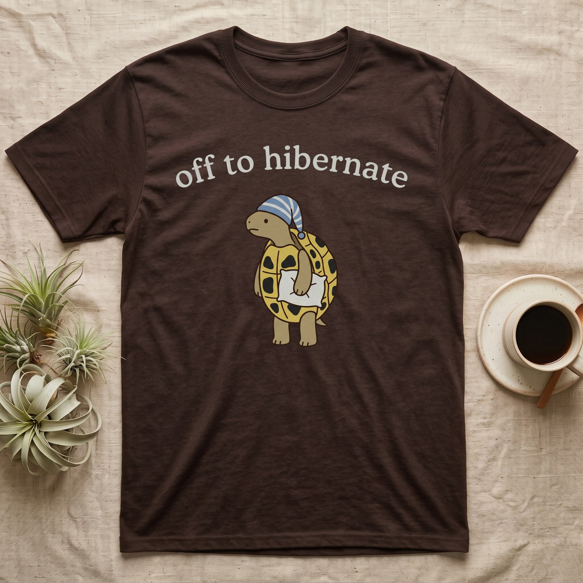 Hermann's Tortoise Hibernation T-Shirt in Dark Chocolate — Minimal doodle of a Hermann's tortoise in a striped nightcap holding a pillow under the words off to hibernate