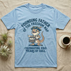 Bearded Dragon Freedom Nap T-Shirt in Light Blue — Cartoon bearded dragon as a drummer boy under arched text Founding Father of the Freedom Nap, 250 Years of Chill.