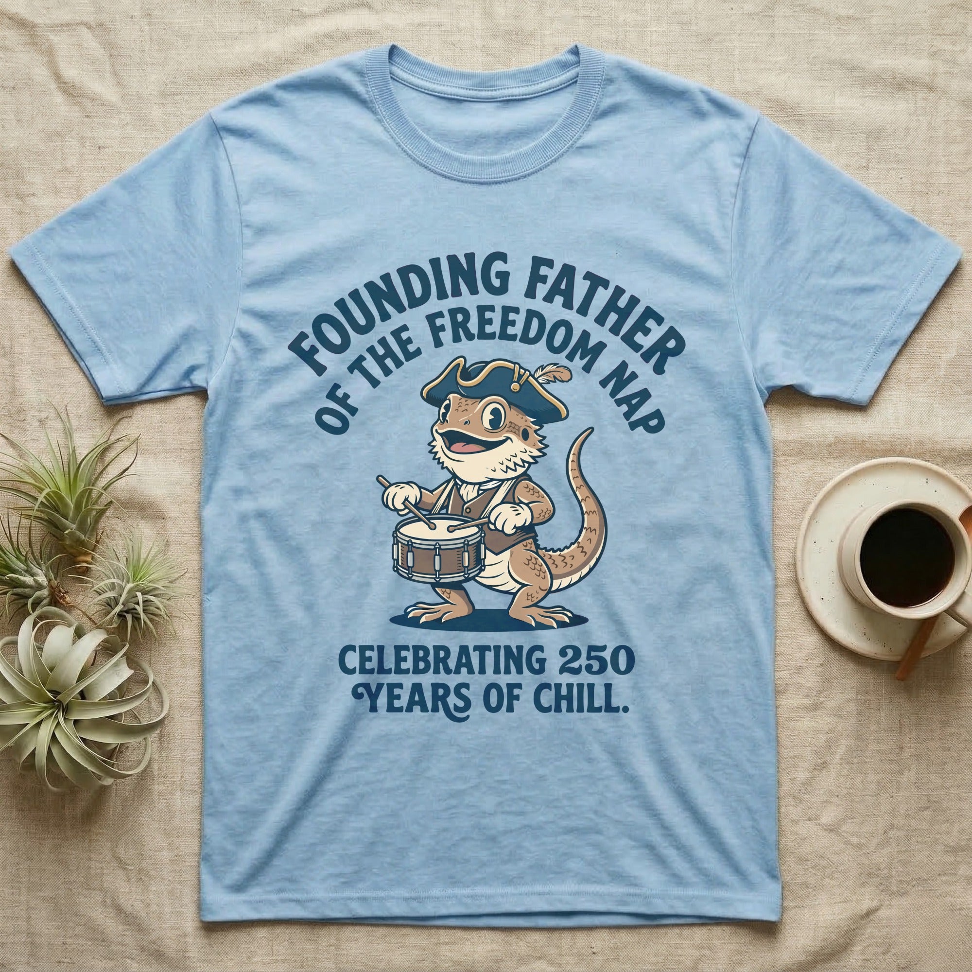 Bearded Dragon Freedom Nap T-Shirt in Light Blue — Cartoon bearded dragon as a drummer boy under arched text Founding Father of the Freedom Nap, 250 Years of Chill.