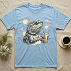 Cold Brew Bearded Dragon T-Shirt in Light Blue — Flat near-photoreal illustration of a bearded dragon in tiny sunglasses holding a cold brew with warm bokeh.