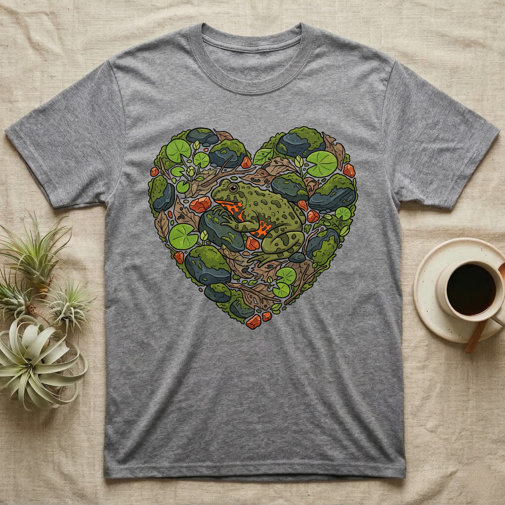 Grey t-shirt with a green frog and heart-shaped natural elements design.