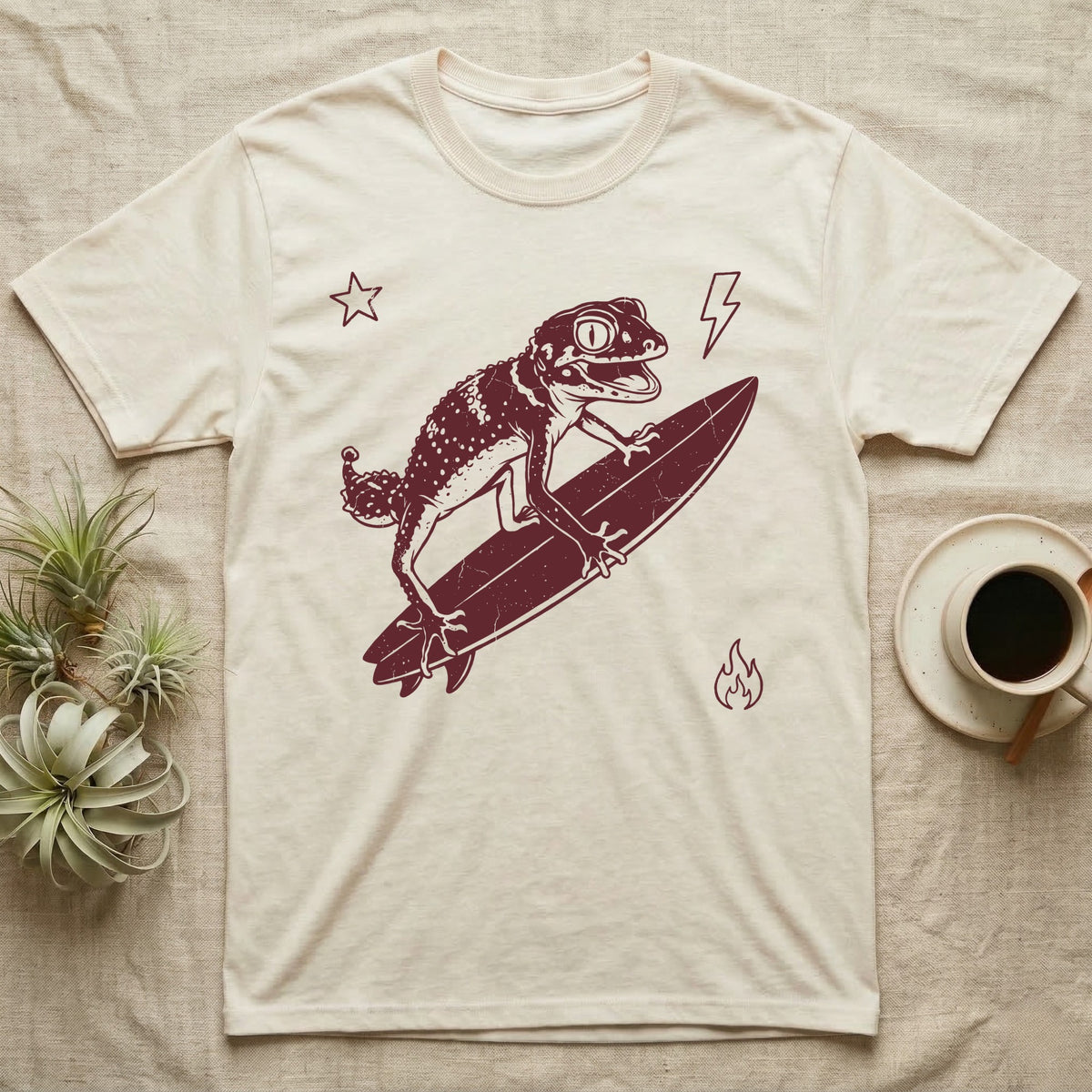 Knob-Tailed Gecko Surfing T-Shirt in Natural — Distressed one-ink illustration of a knob-tailed gecko riding a surfboard, airborne at the peak of an aerial.