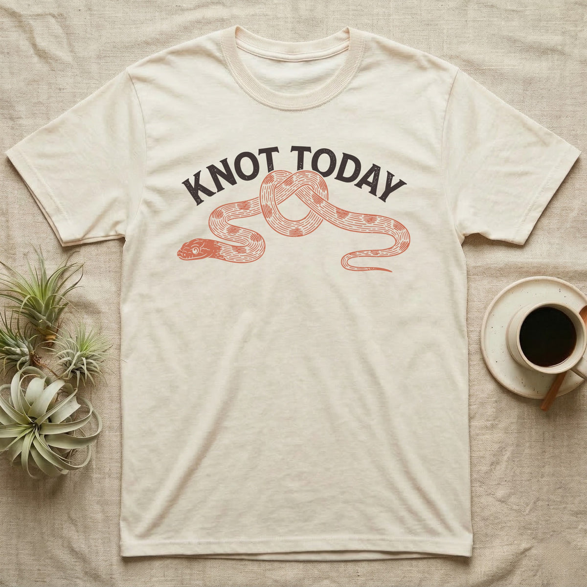 Corn Snake Knot Today T-Shirt in Natural — Worn-stamp corn snake stretched into a half-tied bow beneath a fat arched "KNOT TODAY" headline.