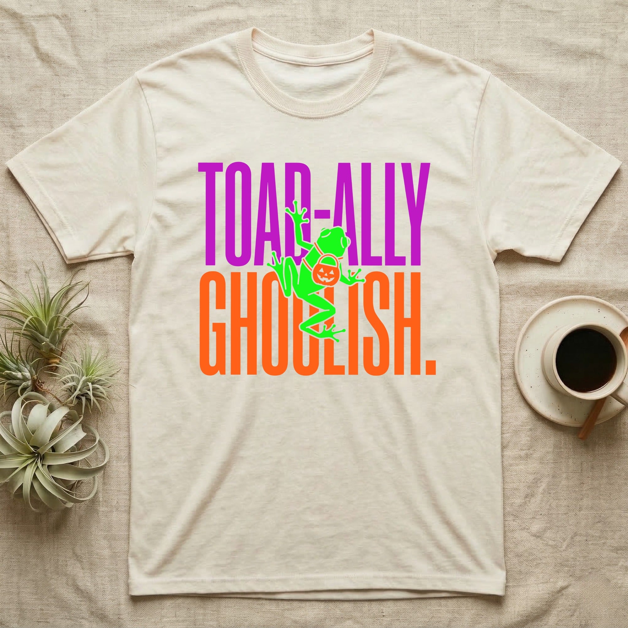 Tree Frog Toad-ally Ghoulish T-Shirt in Natural — Neon green tree frog with a pumpkin pail clinging across stacked text, "Toad-ally Ghoulish."