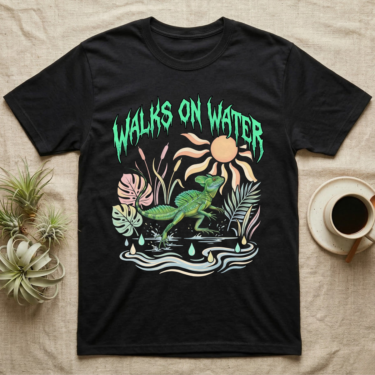 Green Basilisk Feral T-Shirt in Black — Green plumed basilisk sprinting across water below a dripping aqua-green metal "Walks On Water" wordmark