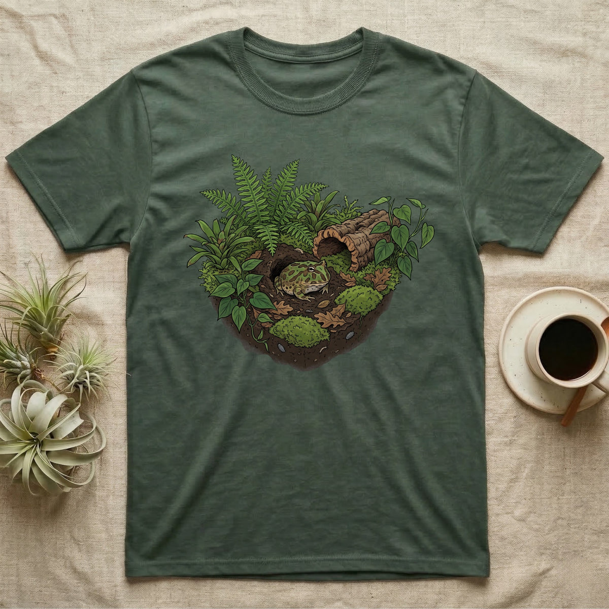 Pacman Frog Vivarium T-Shirt in Military Green — Botanical illustration of a pacman frog thriving in a planted bioactive vivarium beside a small empty plastic cup.