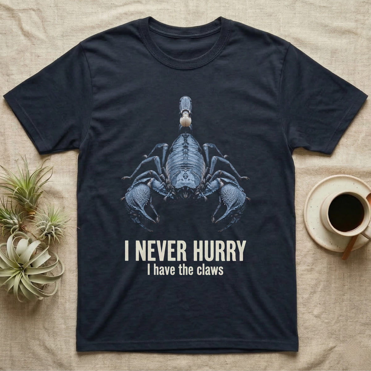 Flat-black mug-shot portrait of an emperor scorpion with claws spread toward the camera, with the printed words I Never Hurry, I have the claws. — shown on a Navy tee.