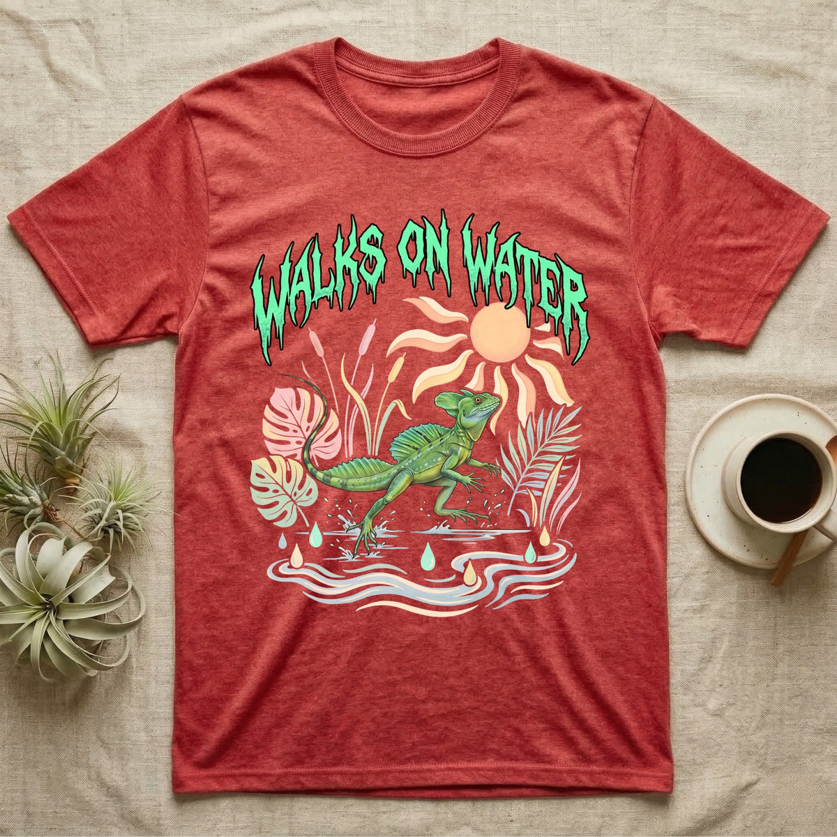 Green Basilisk Feral T-Shirt in Heather Red — Green plumed basilisk sprinting across water below a dripping aqua-green metal "Walks On Water" wordmark