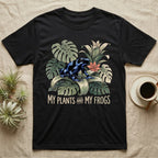 Plants And Frogs T-Shirt in Black — Naturalist-plate illustration of a dart frog perched in lush foliage with hand-lettered text reading My Plants And My Frogs.
