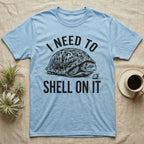 Box Turtle Overthinker T-Shirt in Light Blue — Etching of a box turtle half-closed in its shell beside a strawberry, under I NEED TO, above SHELL ON IT