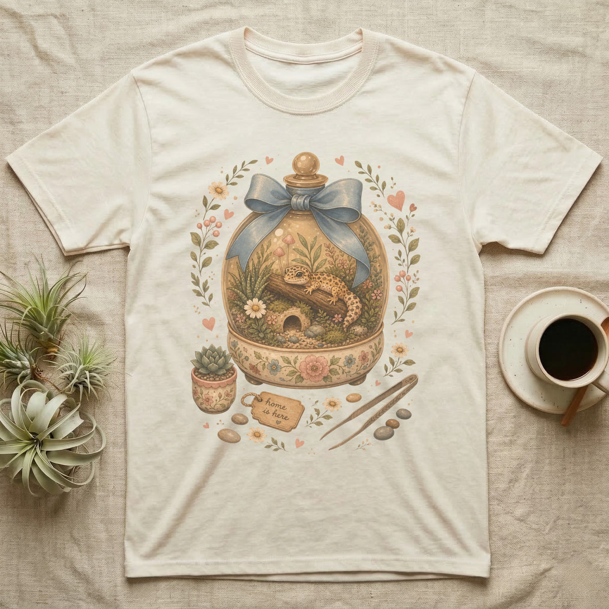 Cream t-shirt featuring a watercolor terrarium with a leopard gecko and "Home is here" tag.